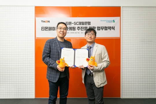 지난 13일 SC제일은행-티몬 공동 마케팅 업무 협약식에 참석한 김종훈 SC제일은행 디지털사업부 상무(왼쪽)와 김준수 티몬 최고마케팅책임자가 기념 촬영을 하고 있다. SC제일은행 제공